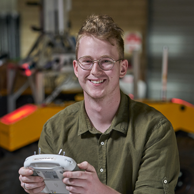 Male defence worker holding robotics controller and smiling at camera 