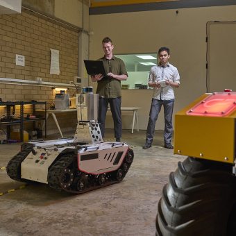 Two male defence workers, working on a defence robot