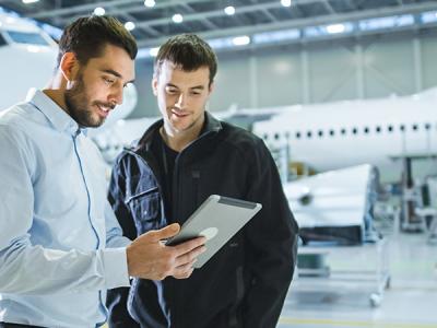 Two engineers looking at an iPad in an aircraft hangar
