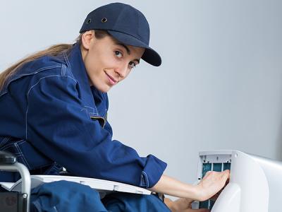 Young woman in baseball cap repairing an appliance