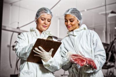 Two women in a meat processing facility looking at a clipboard