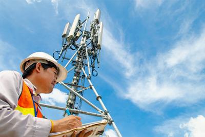 Telecommunications tower with technician looking over.